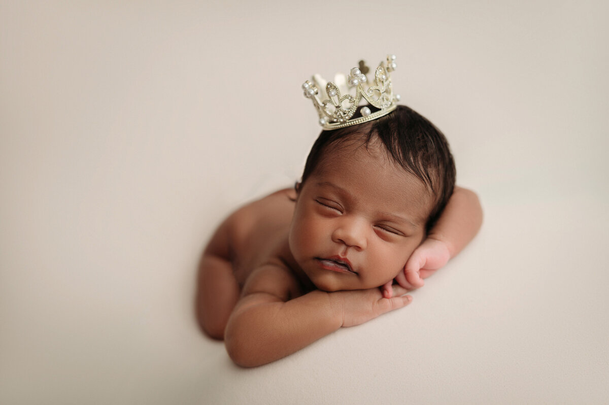 New Haven newborn photographer captures newborn baby girl laying on her belly sleeping and wearing a little royal crown