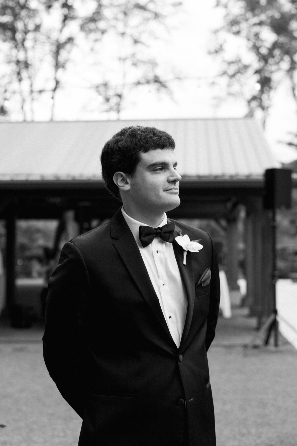 Groom stands at the altar in a classic black tuxedo, waiting for his bride at Sapphire Creek Winery wedding ceremony.