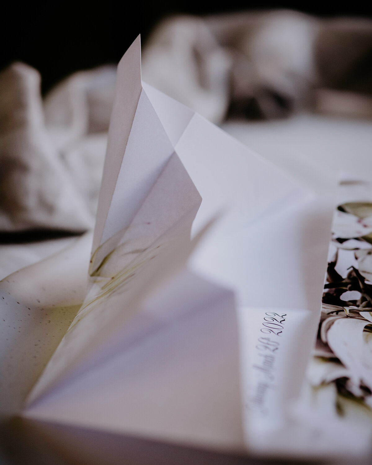 Folds throughout the origami wedding invitation with a cream and black flower image