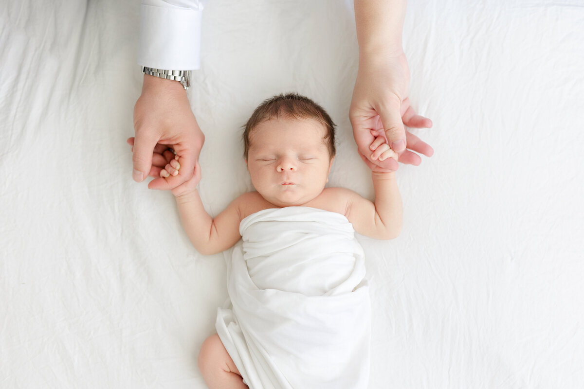 Luxury Tampa newborn portrait in natural light studio with baby wrapped in white swaddle