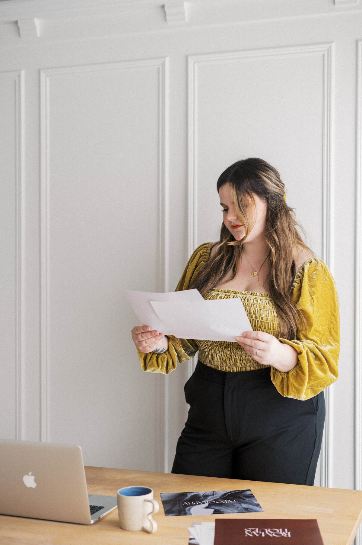 Brand photography of a woman wearing velvet yellow shirt looking through brand design document