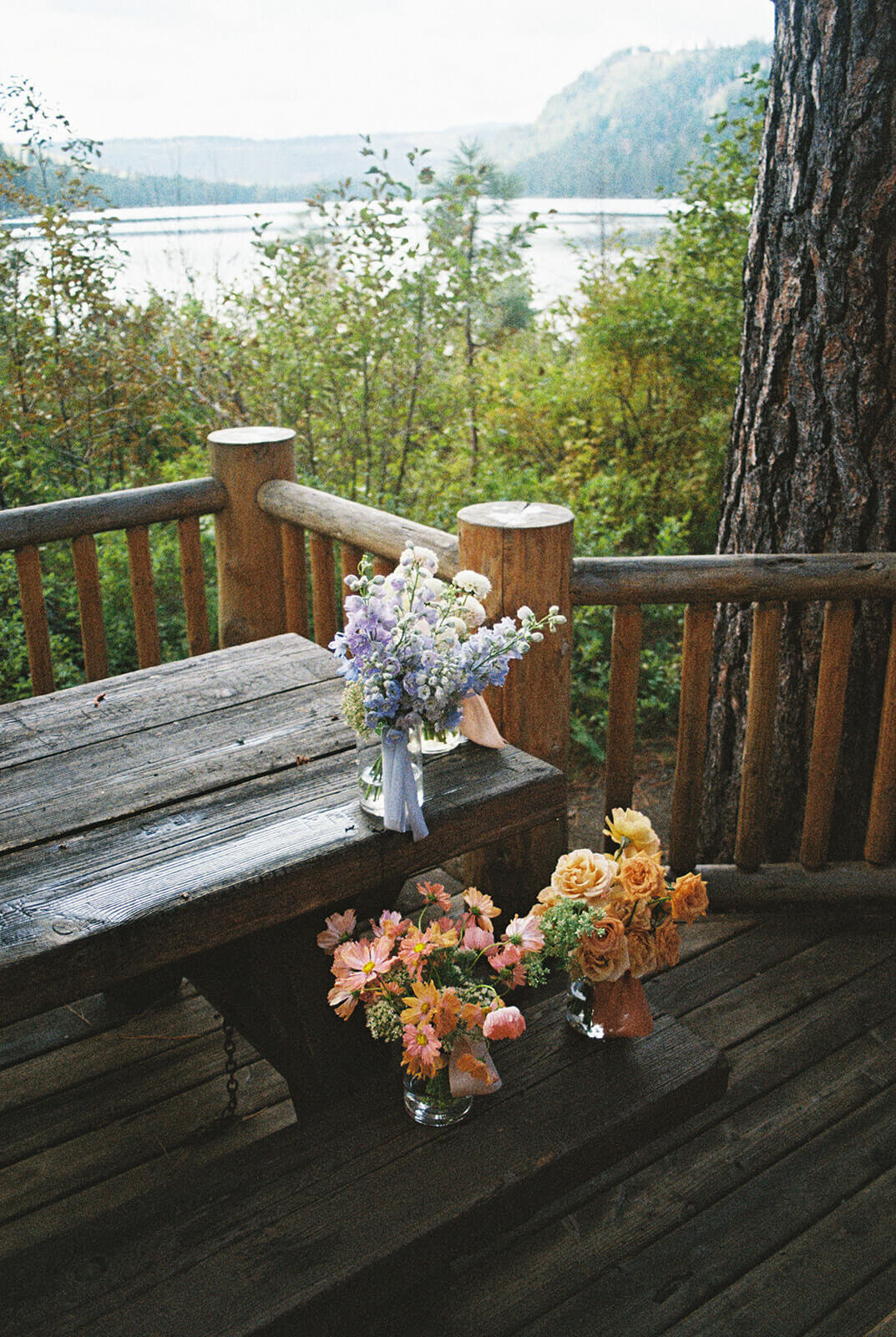 A wooden picnic table with vases of wedding flowers on it. 