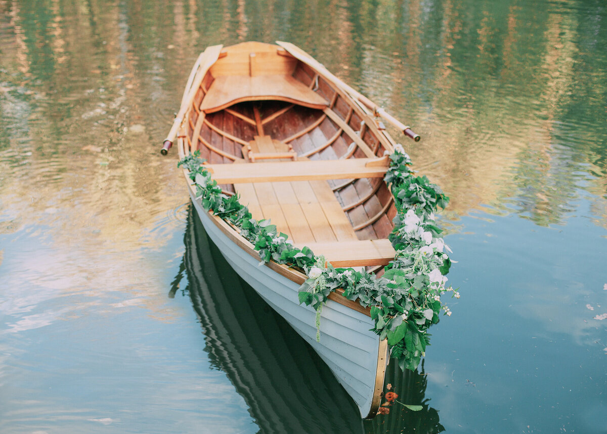 A quaint rowing boat adorned with wedding flowers for a luxury proposal on a lake.