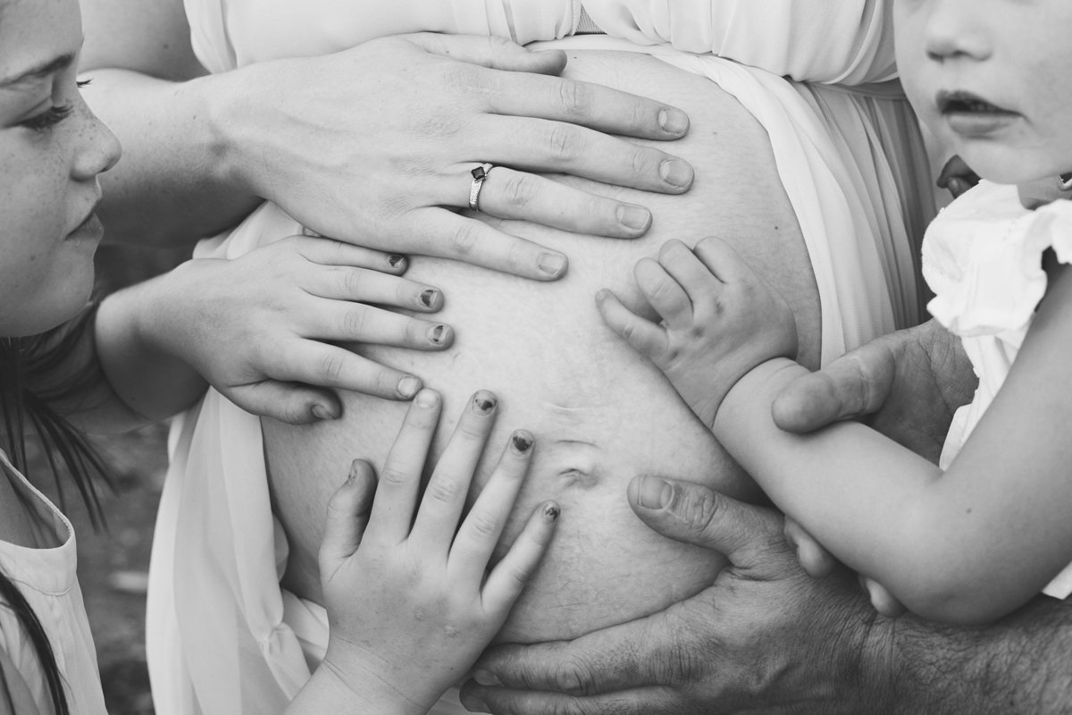 Families hands on pregnant womens stomach