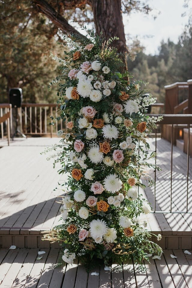 A floral installation decorates the ceremony site for an outdoor wedding.