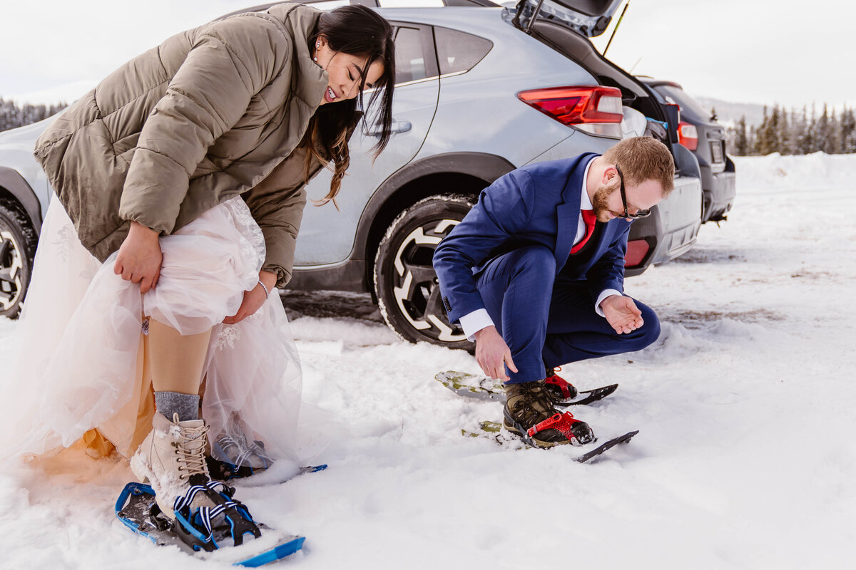 Bride and groom snowshoe through fresh powder during their adventurous winter elopement in Colorado.