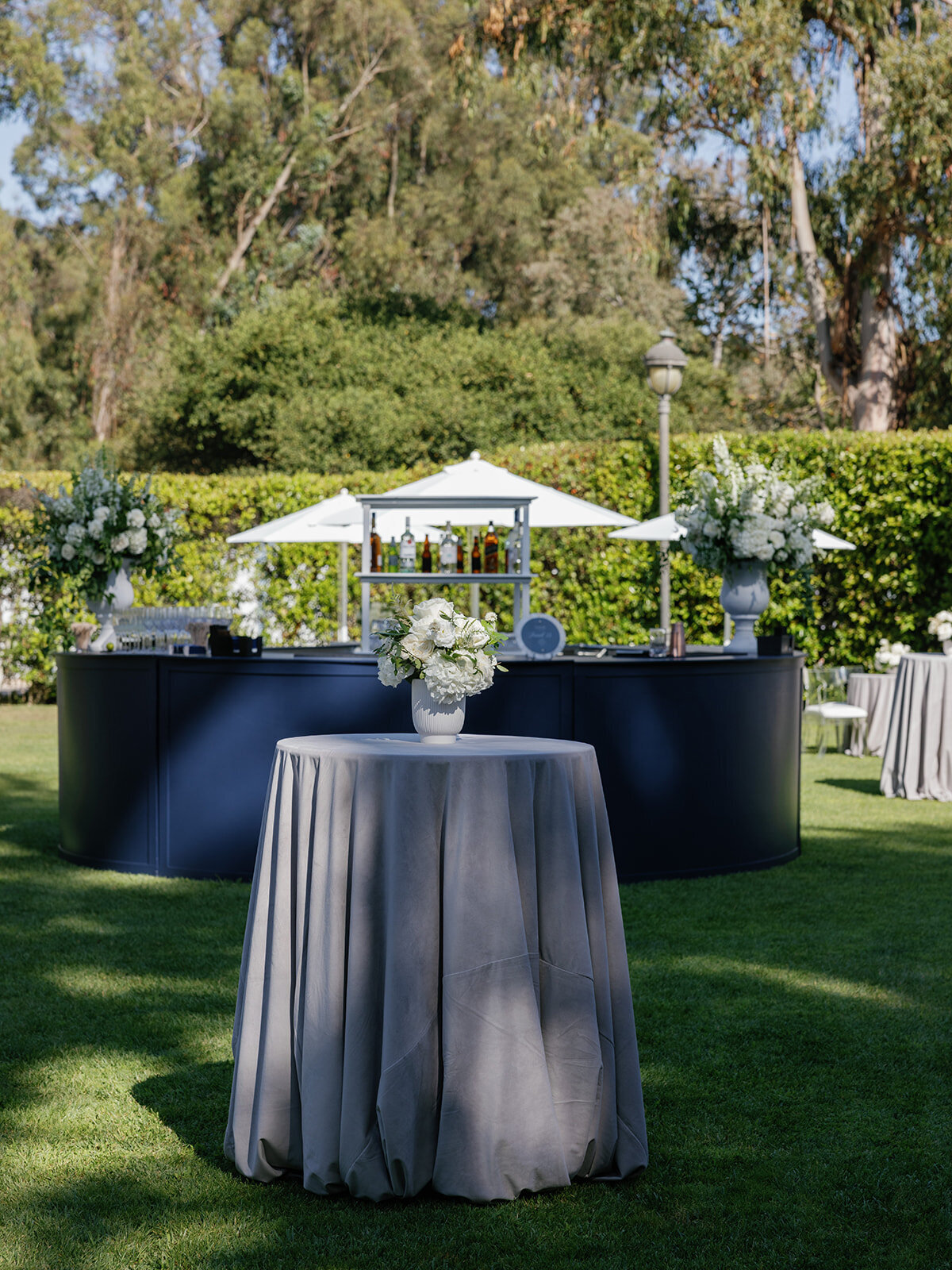Navy blue cocktail hour at The Ritz Carlton Bacara with velvet linens, white flowers, and navy blue round statement bar