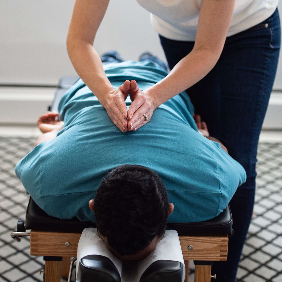 a male laying face down on a table gets his back adjusted by a female chiropractor.  Captured by Ottawa Branding Photographer JEMMAN Photography Commercial