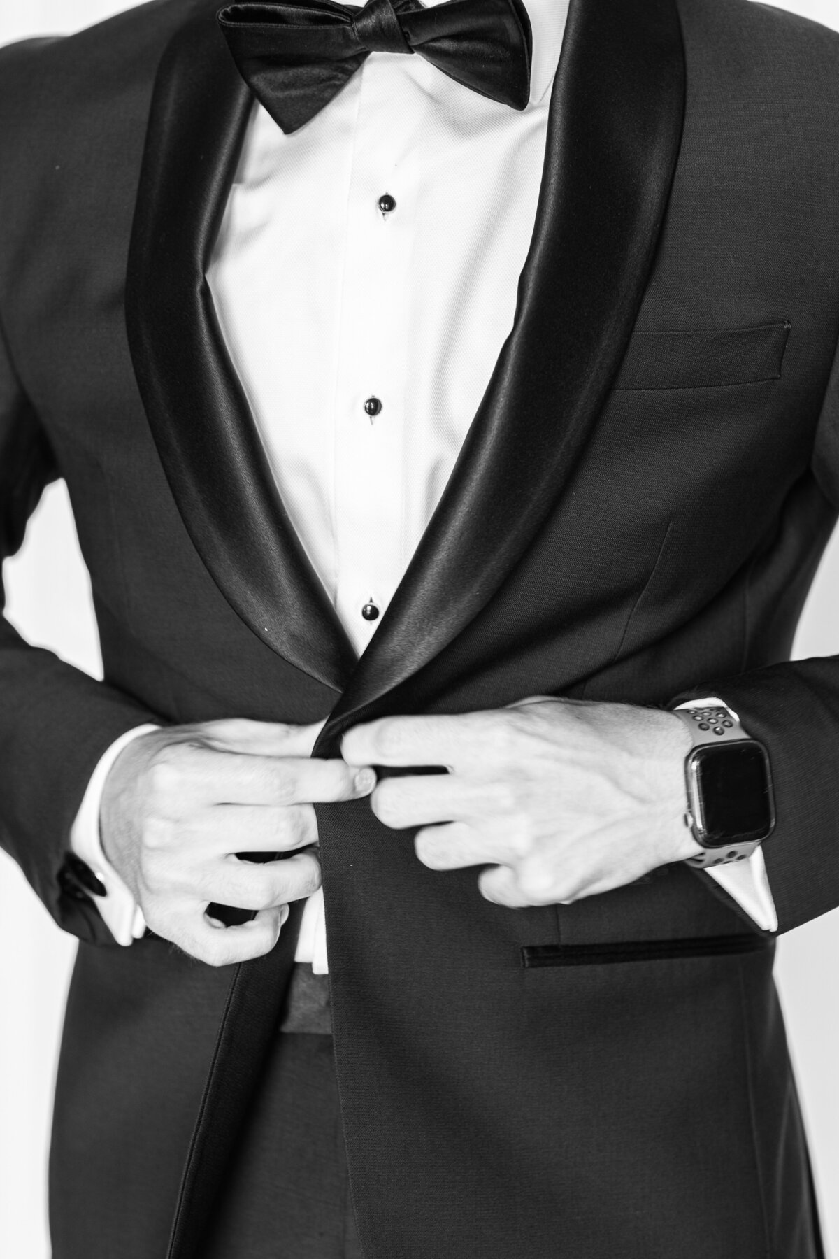 Close up of groom buttoning his tuxedo representing Boston wedding groom portraits