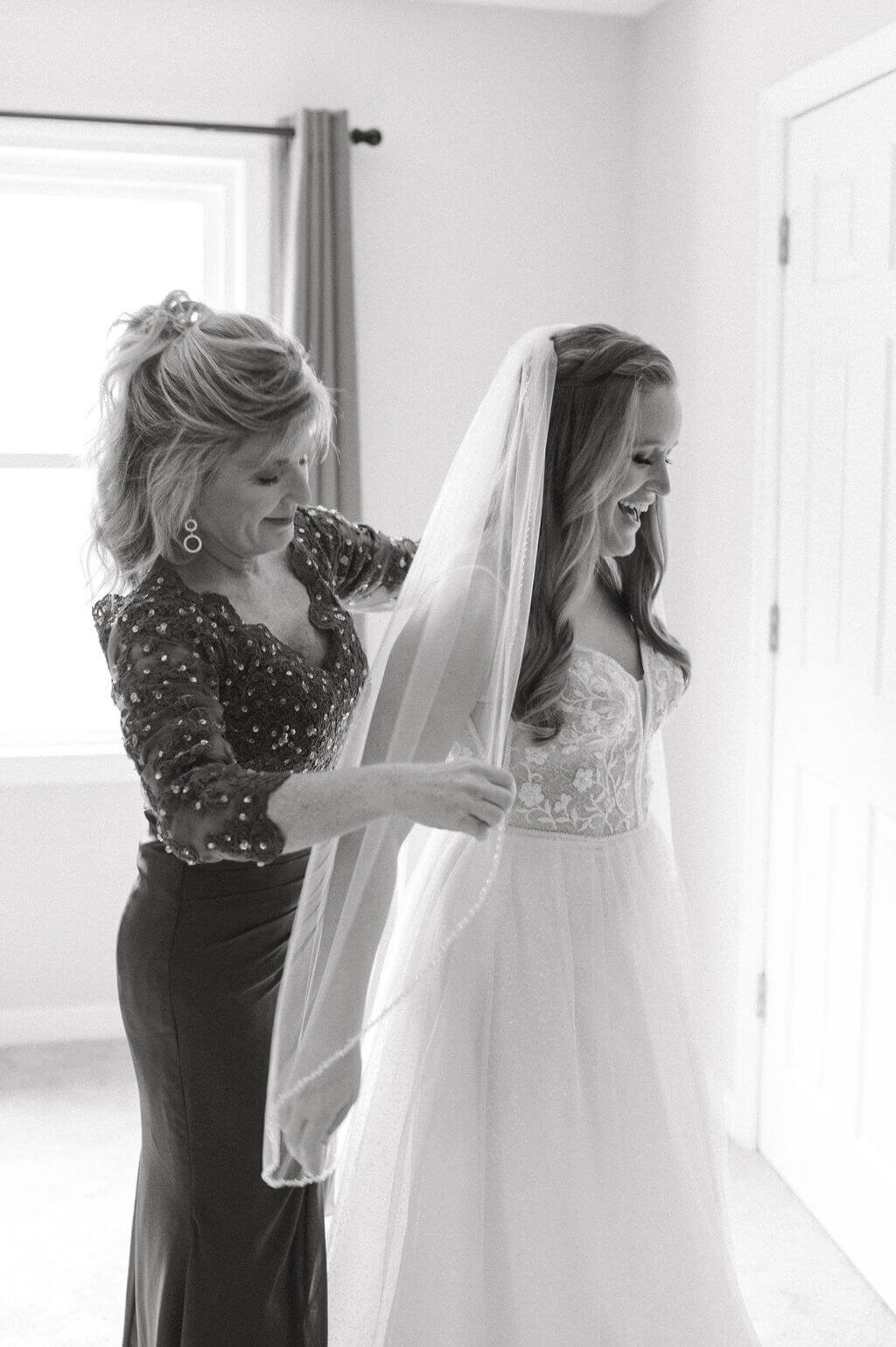 Intimate image of bride's mother fixing her veil during getting ready photos