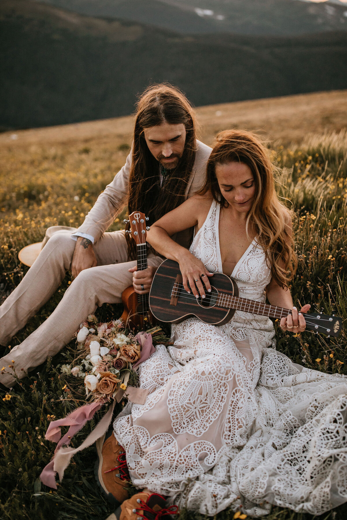 bride and groom wearing white and ivory sitting outdoors holding ukuleles