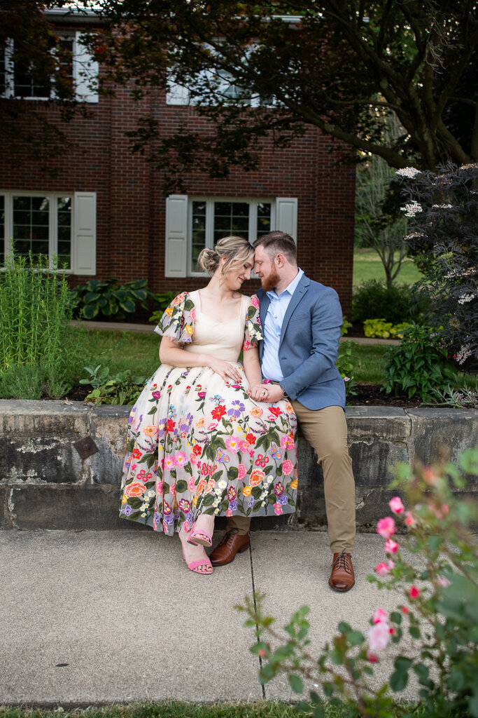 Couple sits with foreheads touching in front of the brick home at Canton Garden Center