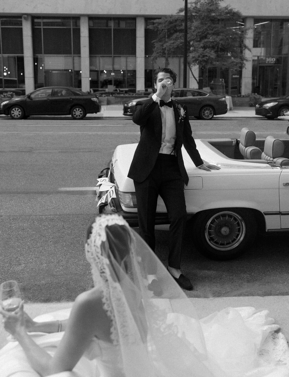 documentary, editorial film wedding photography in Detroit shows a groom sipping wine while his bride watches