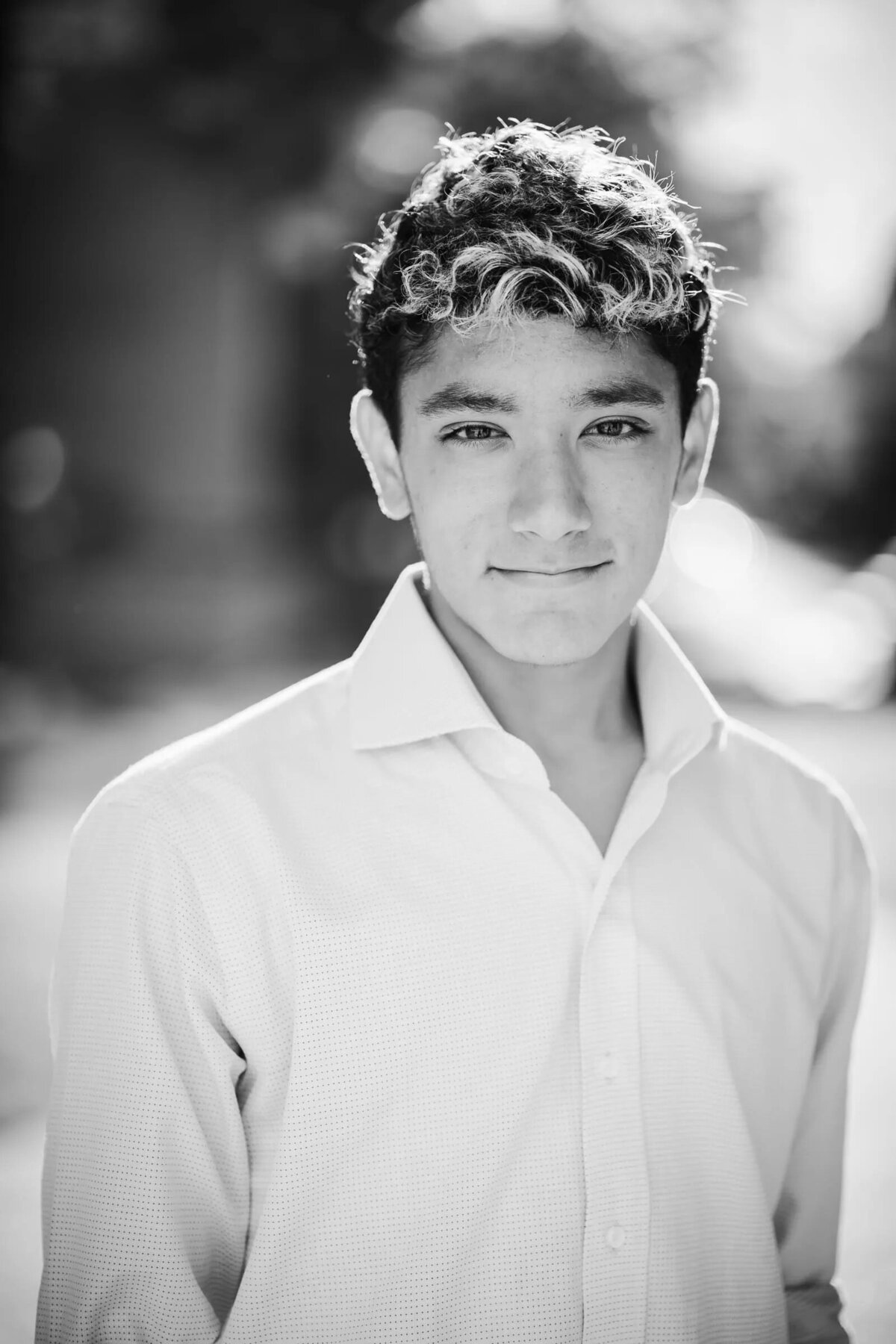 A black and white photo of a boy in a button up shirt with a slight smile.