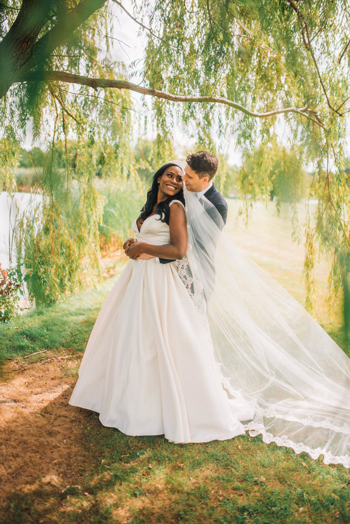 bride and groom romantically looking at each other under a willow tree