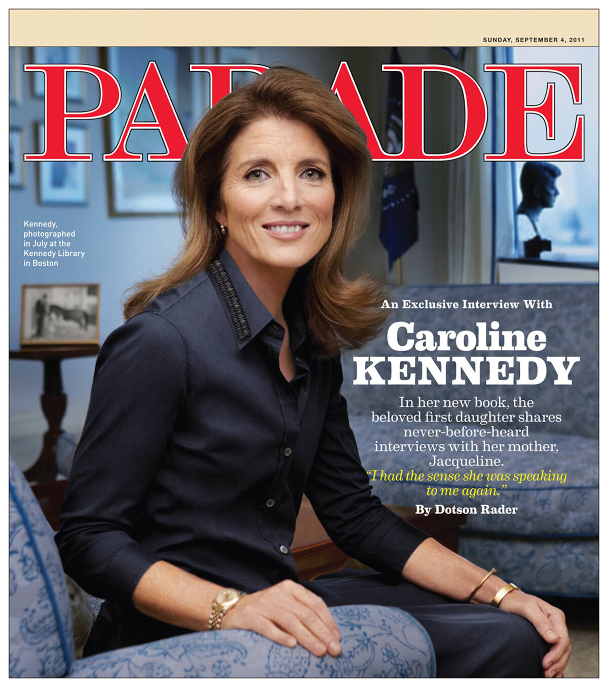 This is a portrait of Ambassador Caroline Kennedy seated on a couch looking into the camera. The couch is in the JFK presidential library. A bust of President Kennedy and an American flag are in the background.