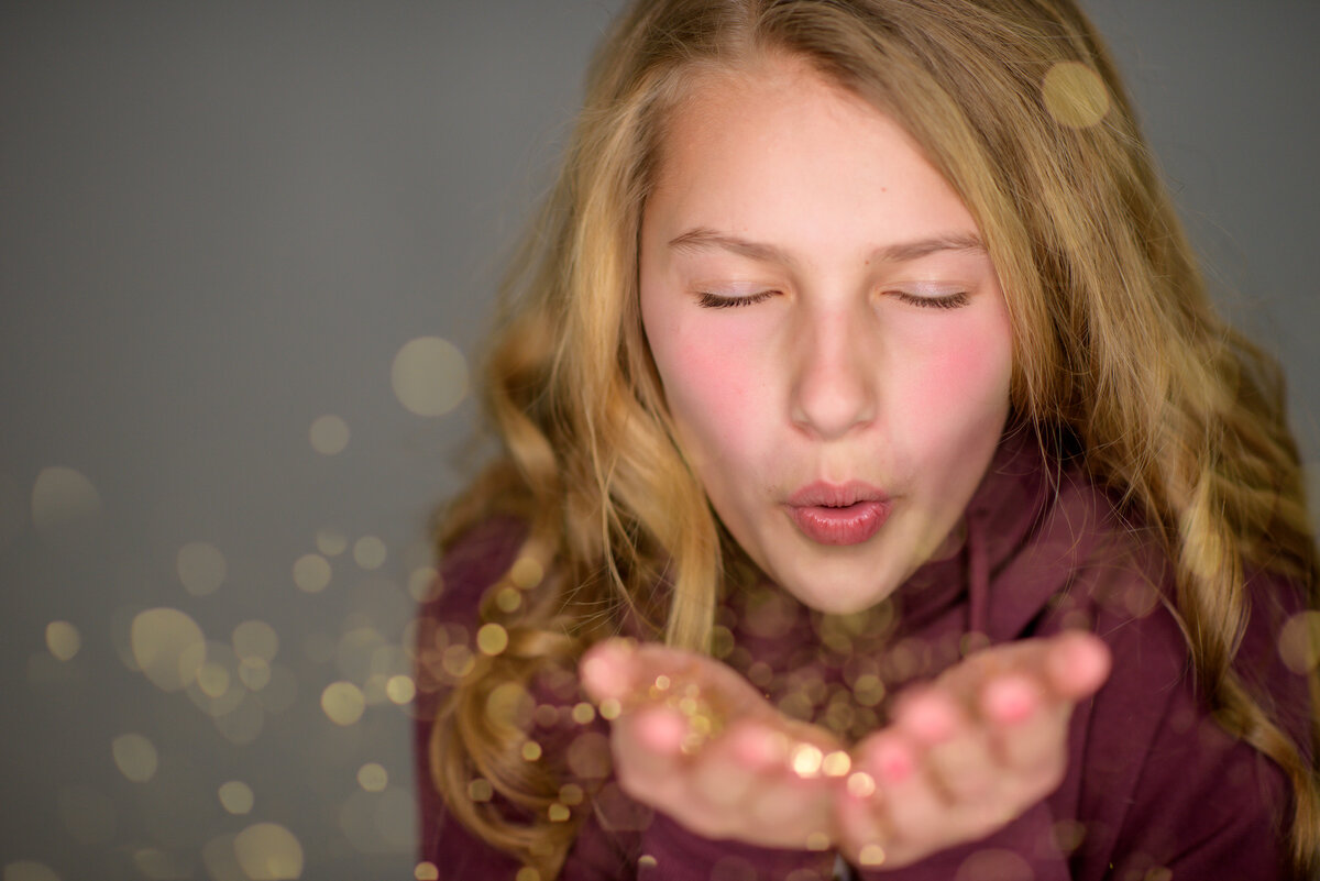 Tween girl blowing glitter in photo studio in Boise.