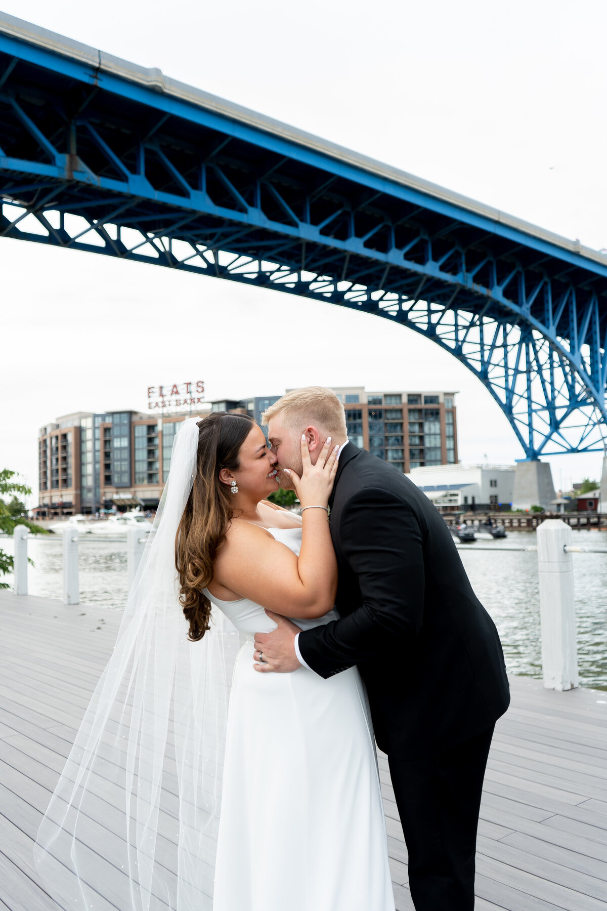couple kissing among Cleveland skyline in the Flats with soft evening light on wedding day