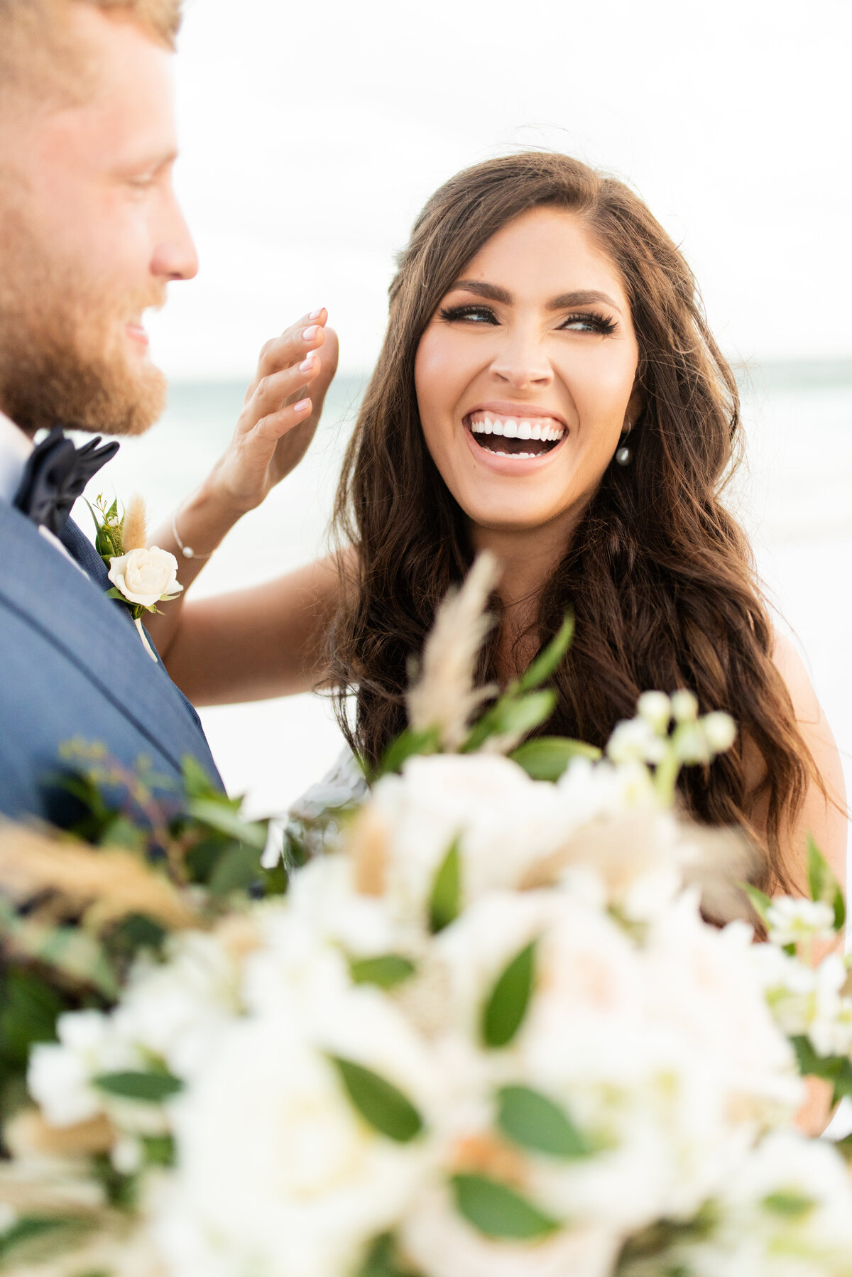 bride and groom on beach laughing