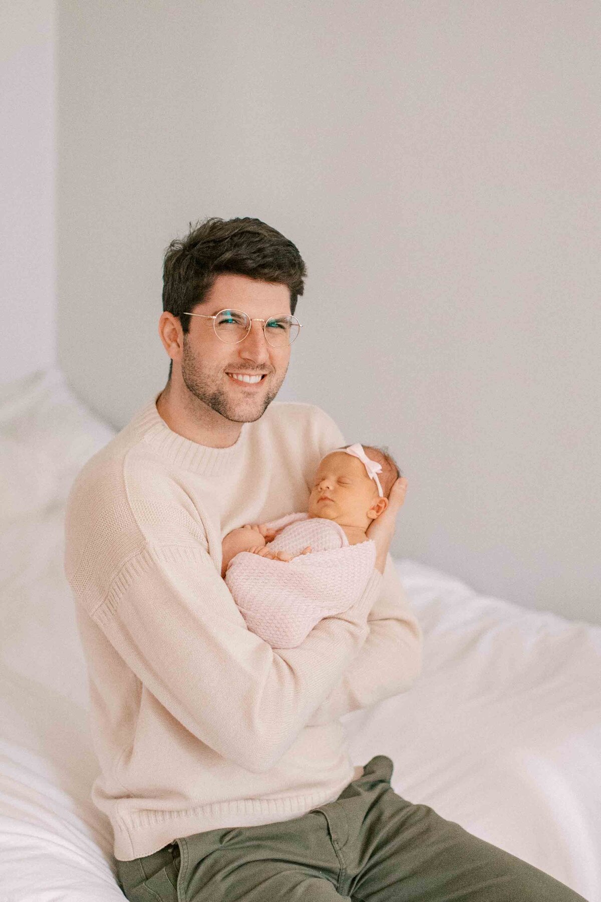 new dad smiling and holding his newborn baby girl