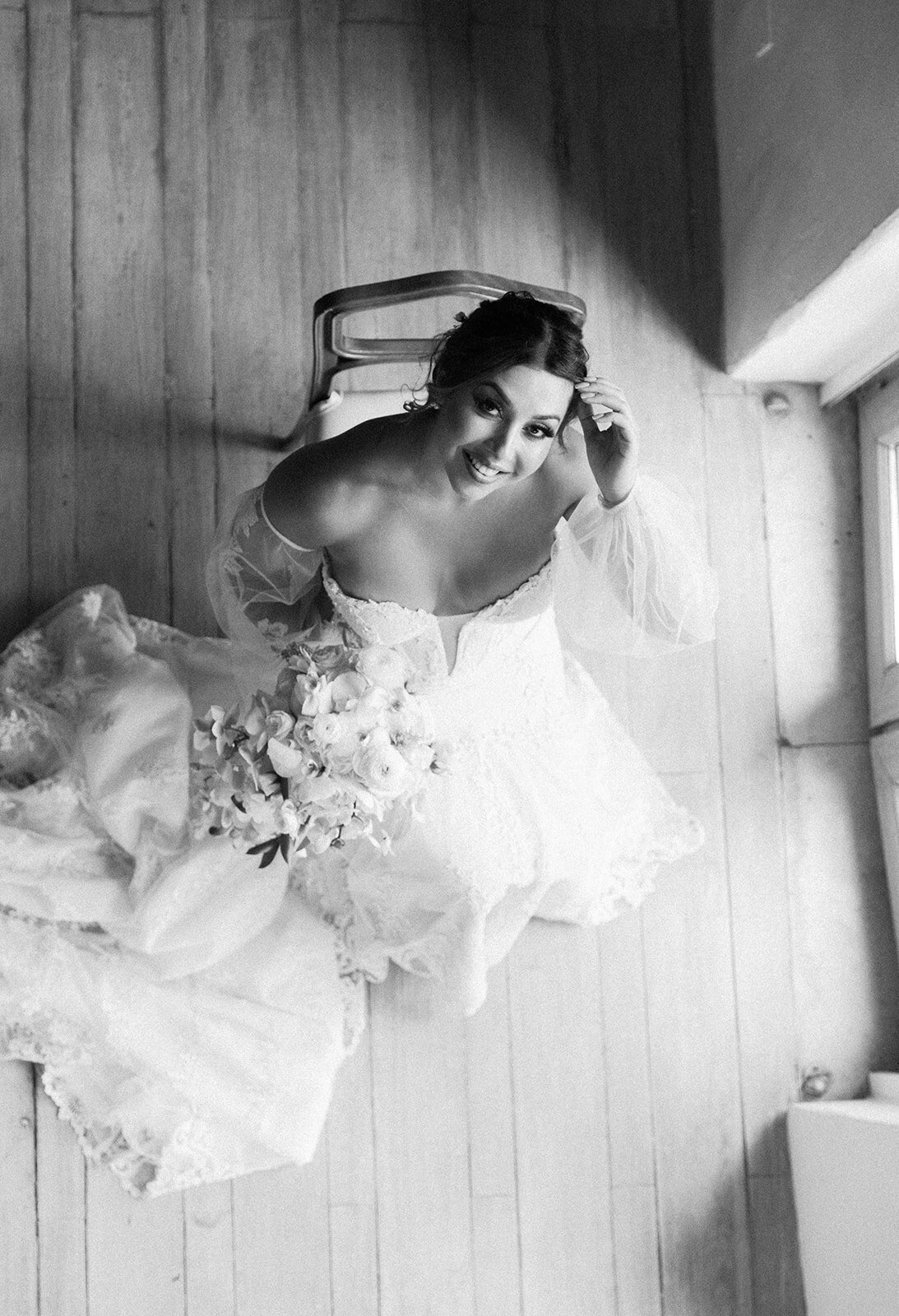 A unique black-and-white overhead portrait of Victoria, beaming in her wedding dress while holding her bridal bouquet.