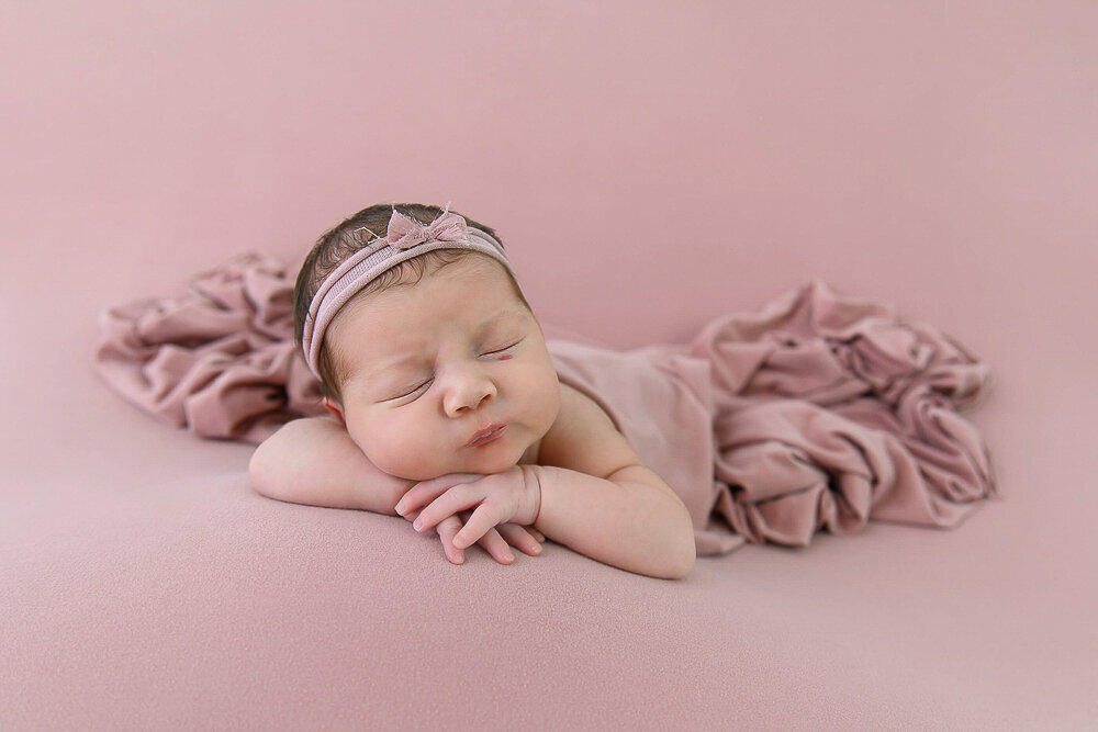 newborn baby girl on an all pink monochrome set.