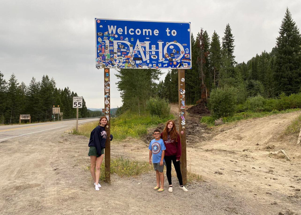 three children standing in front of a sign that says Idaho
