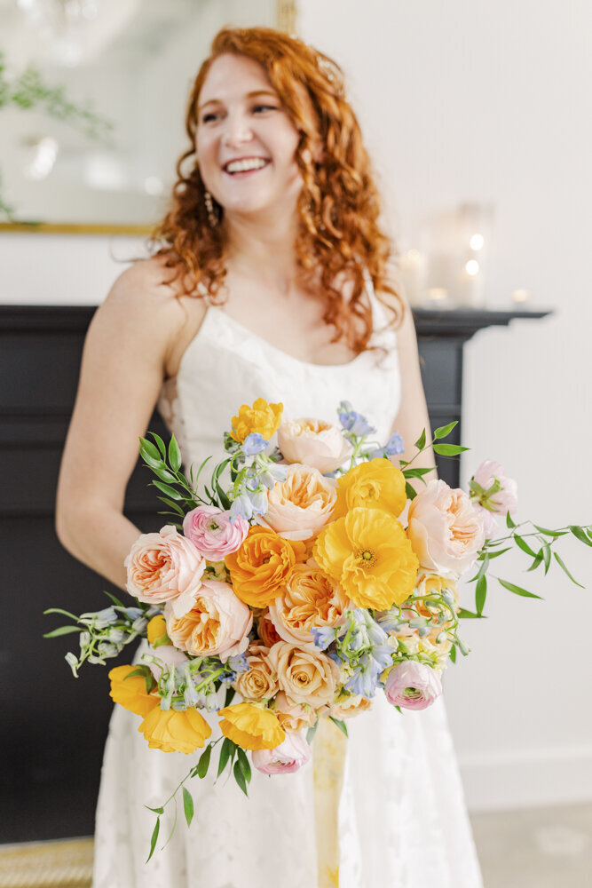 bride smiling while holding a colorful bouquet of flowers