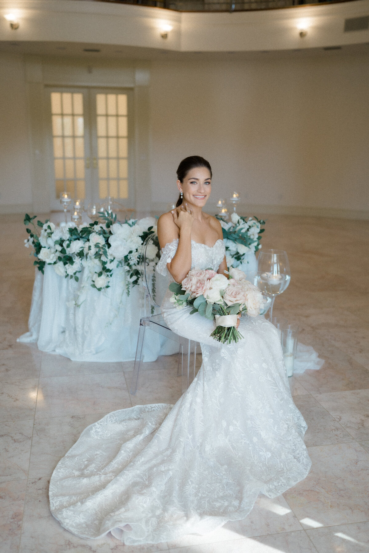 Bride sitting gracefully in front of an elegantly decorated sweetheart table adorned with lush florals and candlelight, designed by In Full Bloom Event Planning & Design