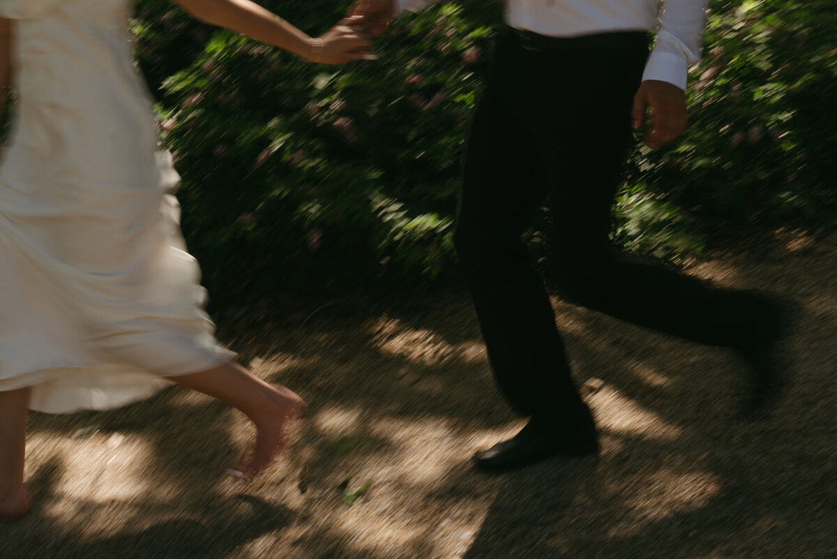 a motion blur photo of a wedding couple running down a gravel road under beautiful oak trees.