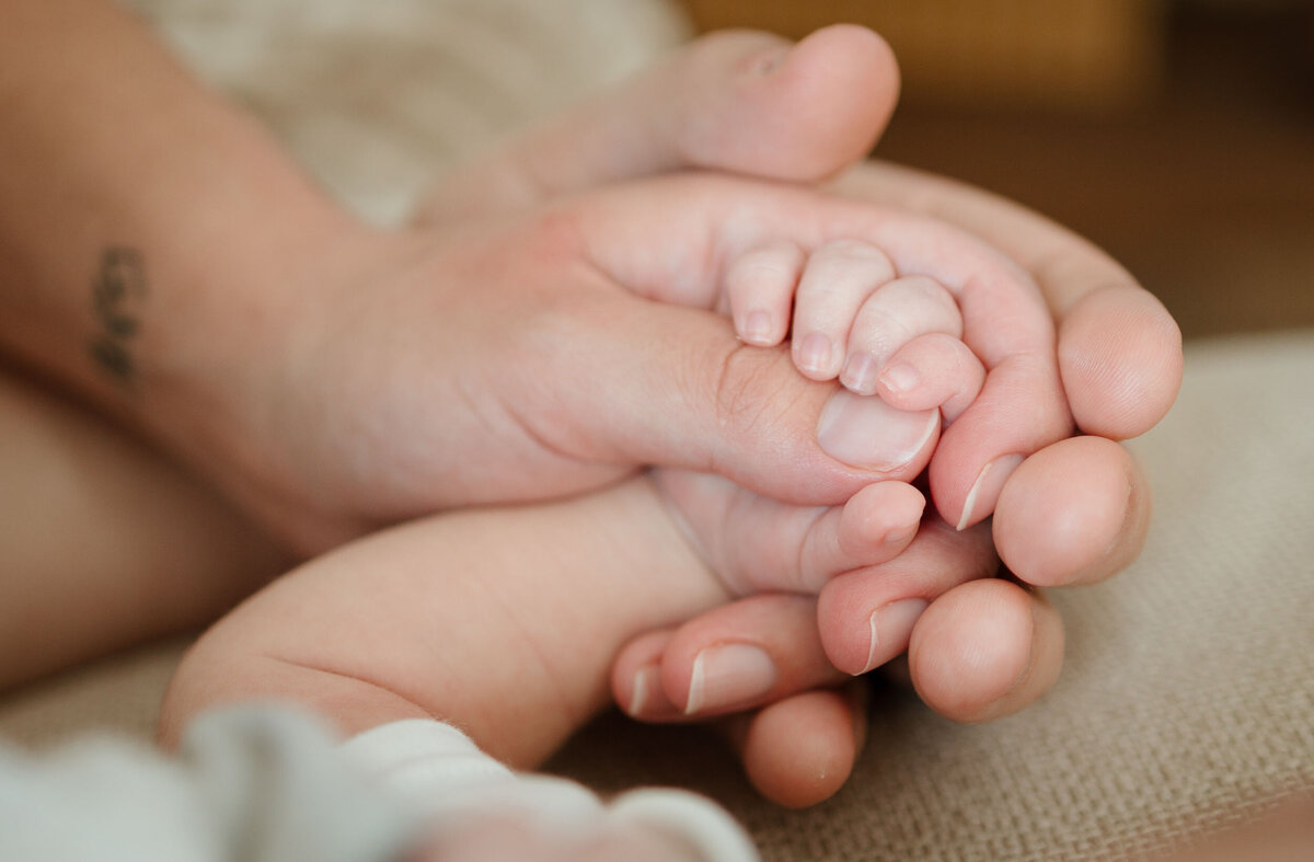 baby holding moms thumb