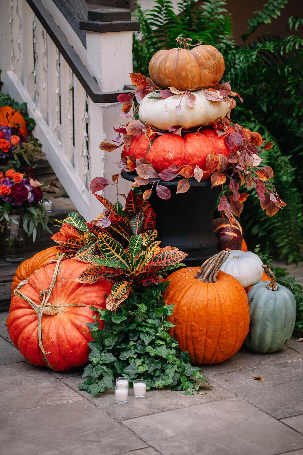 Colorful pumpkins, vines, and greenery decorate wooden steps with white railings.