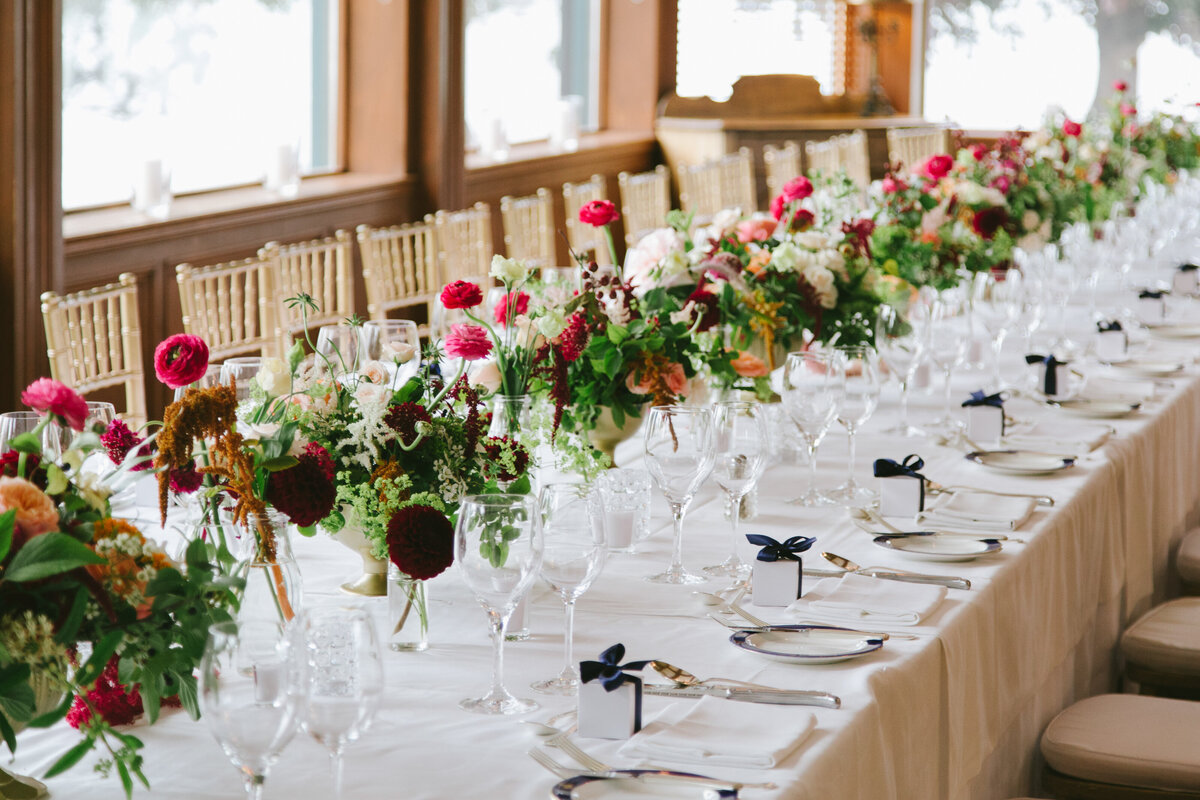 Bright garden floral centrepieces decorate a table at a Forest and Stream Club wedding reception.
