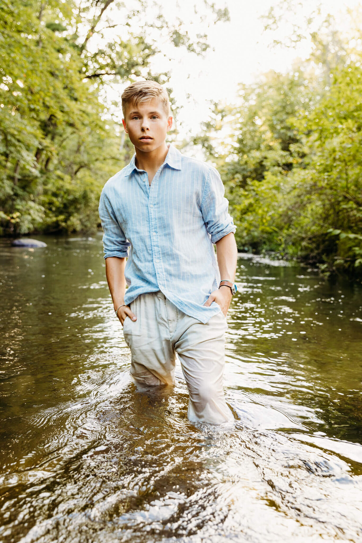 teen boy standing in a creek with hands in his pocket near Green Bay