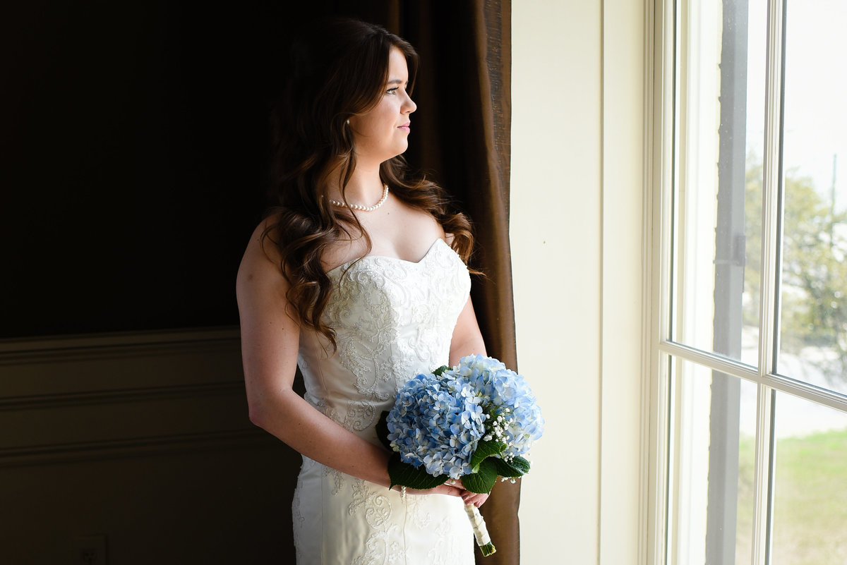 Beautiful bridal portrait photography: Bride gazes out a window at the Biloxi Visitors Center in Biloxi Mississippi