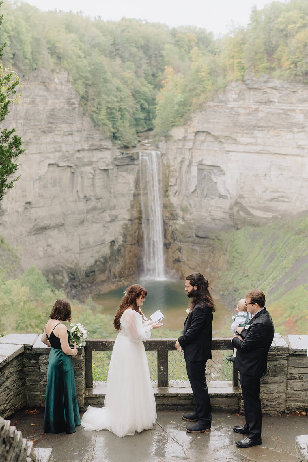 Bride and groom exchanging vows in front of a waterfall at Finger Lakes wedding, NY