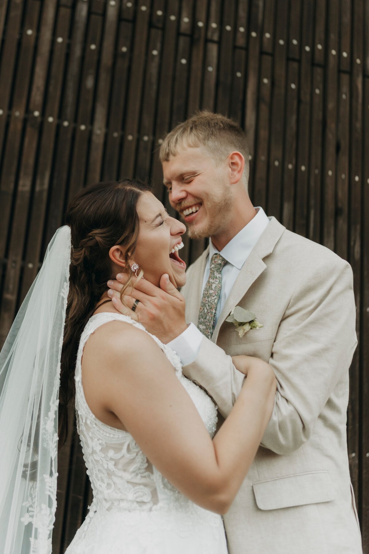 bride and groom holding each other while laughing