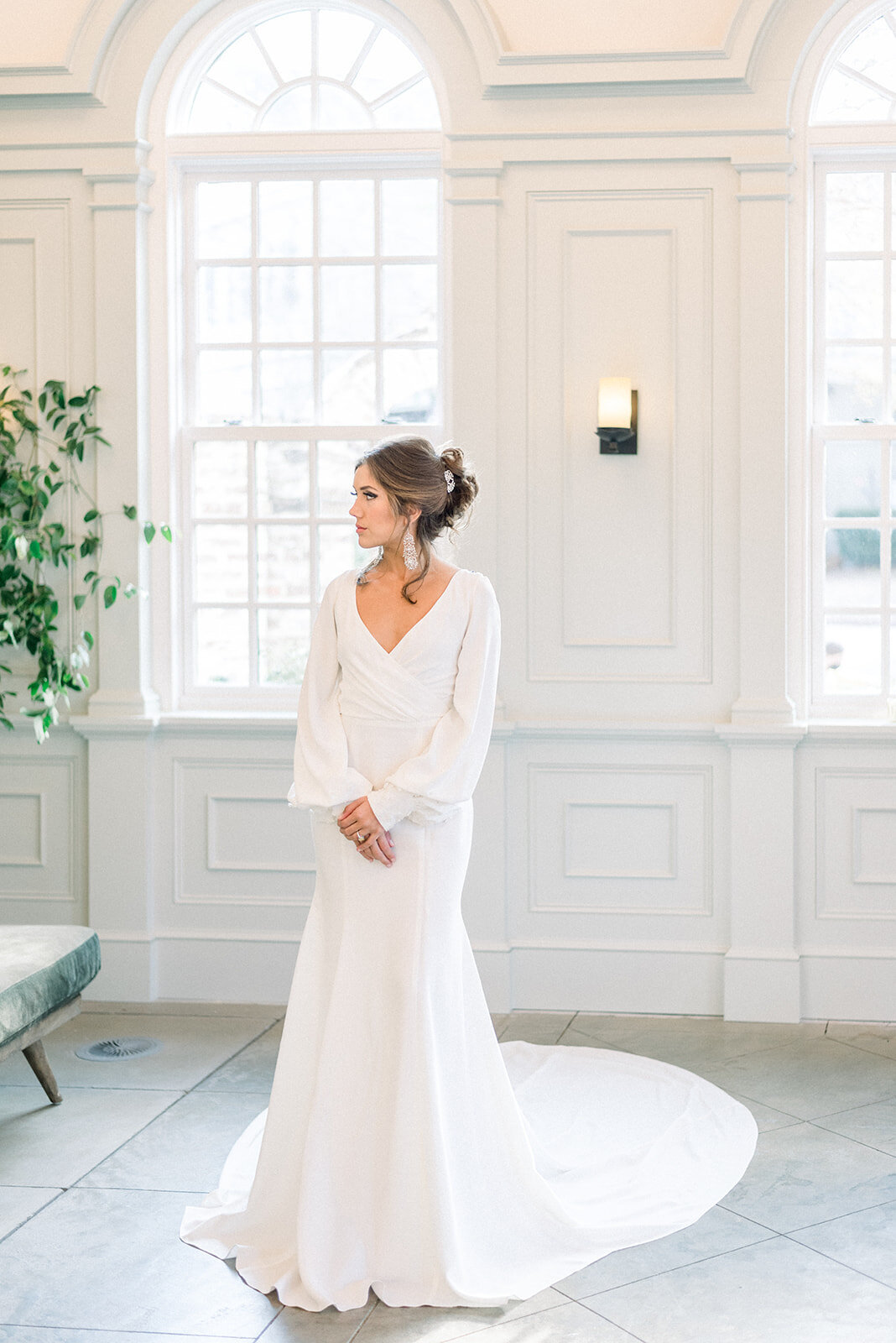 The faux-wrap bodice, bishop sleeves, cathedral train, and clean silhouette create a truly timeless bridal style in Milly.