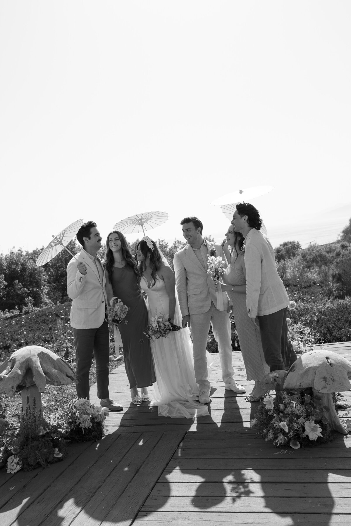 Candid photo of the wedding party sharing a group hug after the couple says 'I do,' encapsulating the joy of the day in La Jolla in San Diego, California.