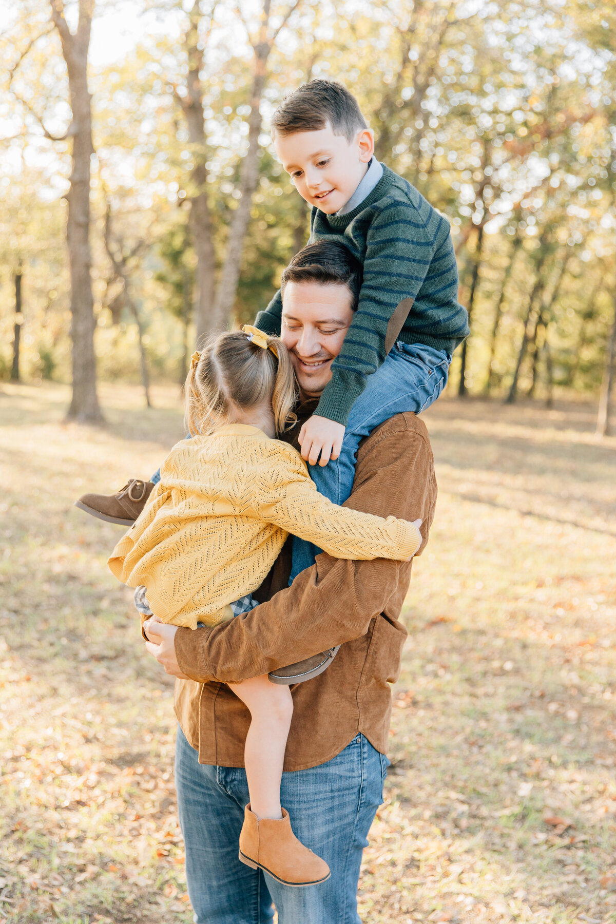 Fatherhood picture of a dad holding both of his children in a beautiful woodsy setting located in Flower Mound, TX