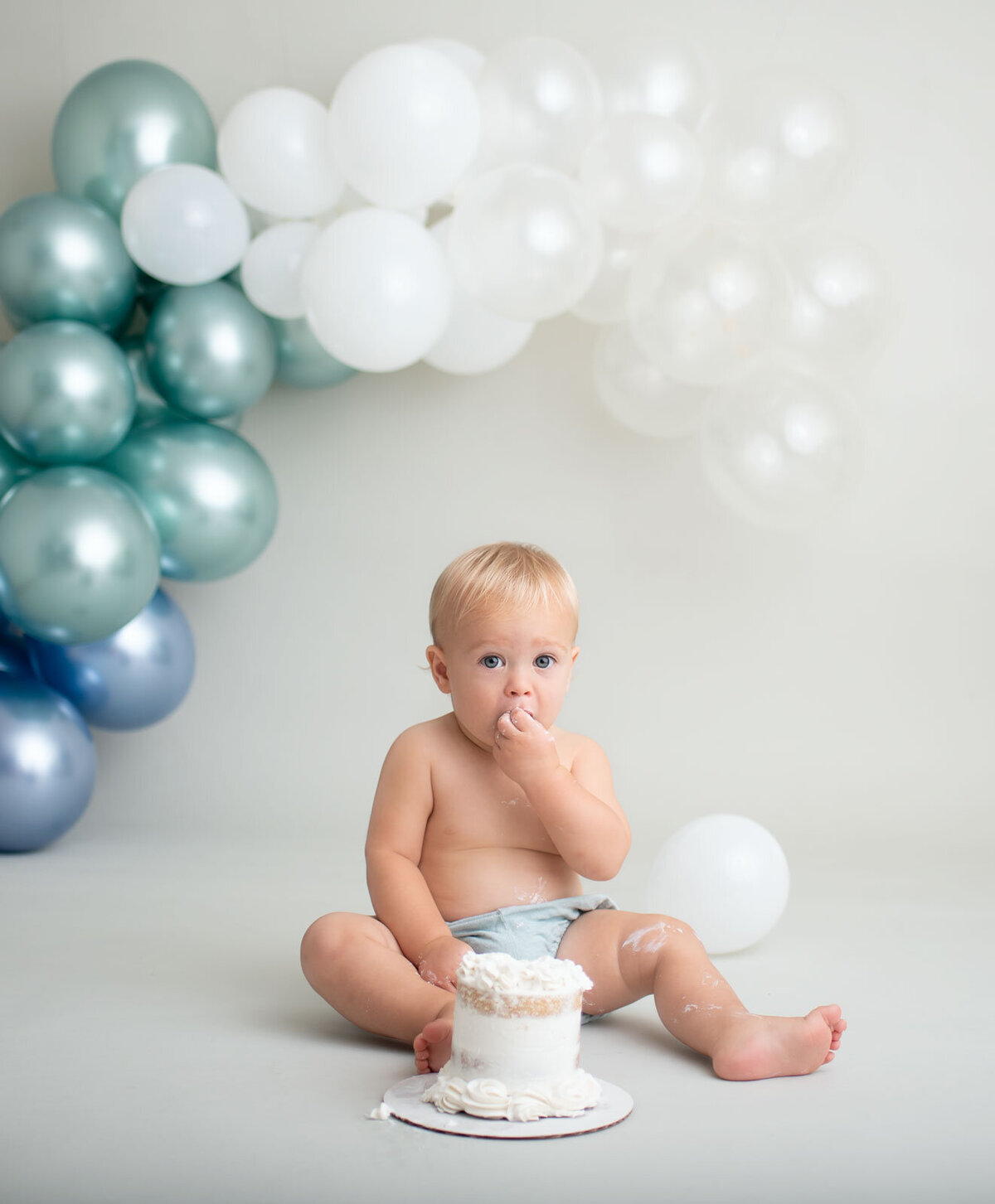 baby eating cake by sutherland photography, a st. louis cake smash photographer