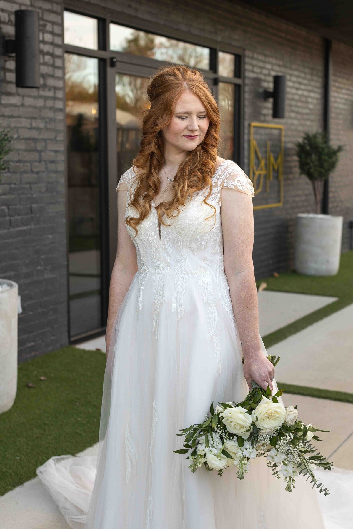 Bride holding wedding bouquet down at her side while she smiles