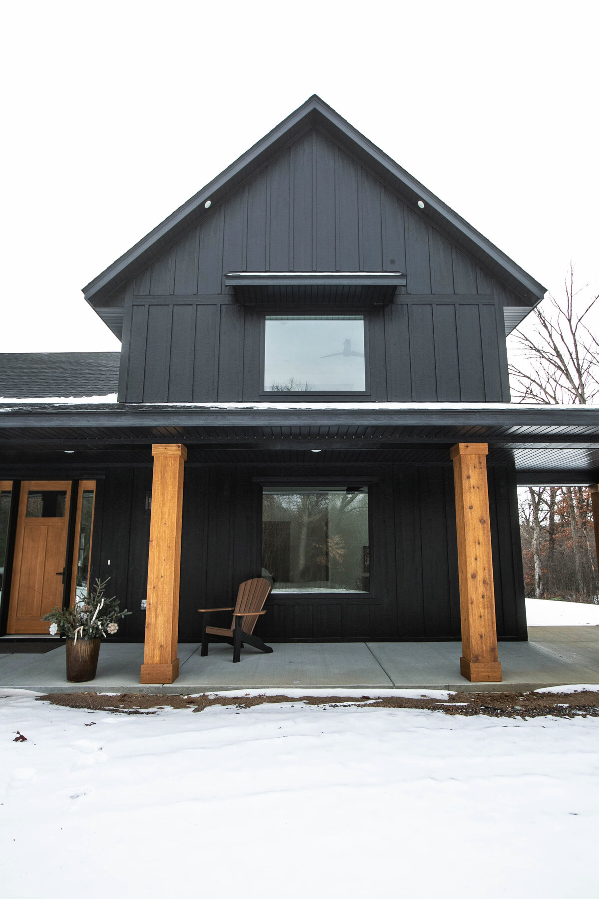 Exterior view of custom home in Elk River, Minnesota with black siding, wood details and front porch built by Cornerstone Custom Builds