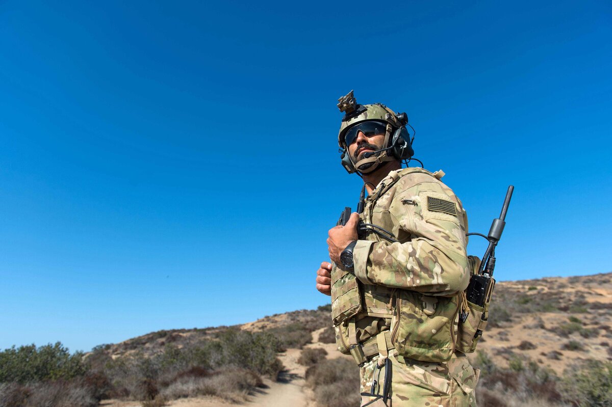 A marine is photographed looking off in distance with tactical gear in desert.