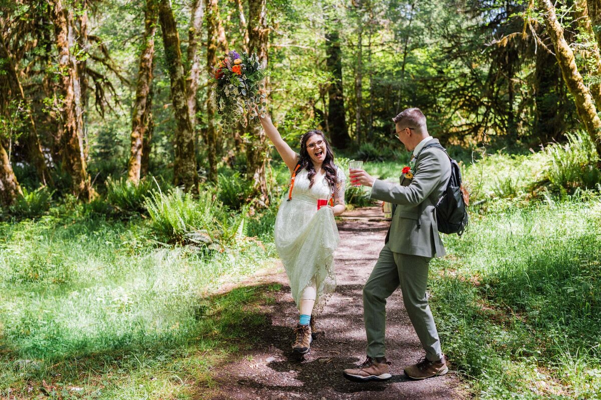 hiking couple in wedding attire cheering on a forested Washington trail