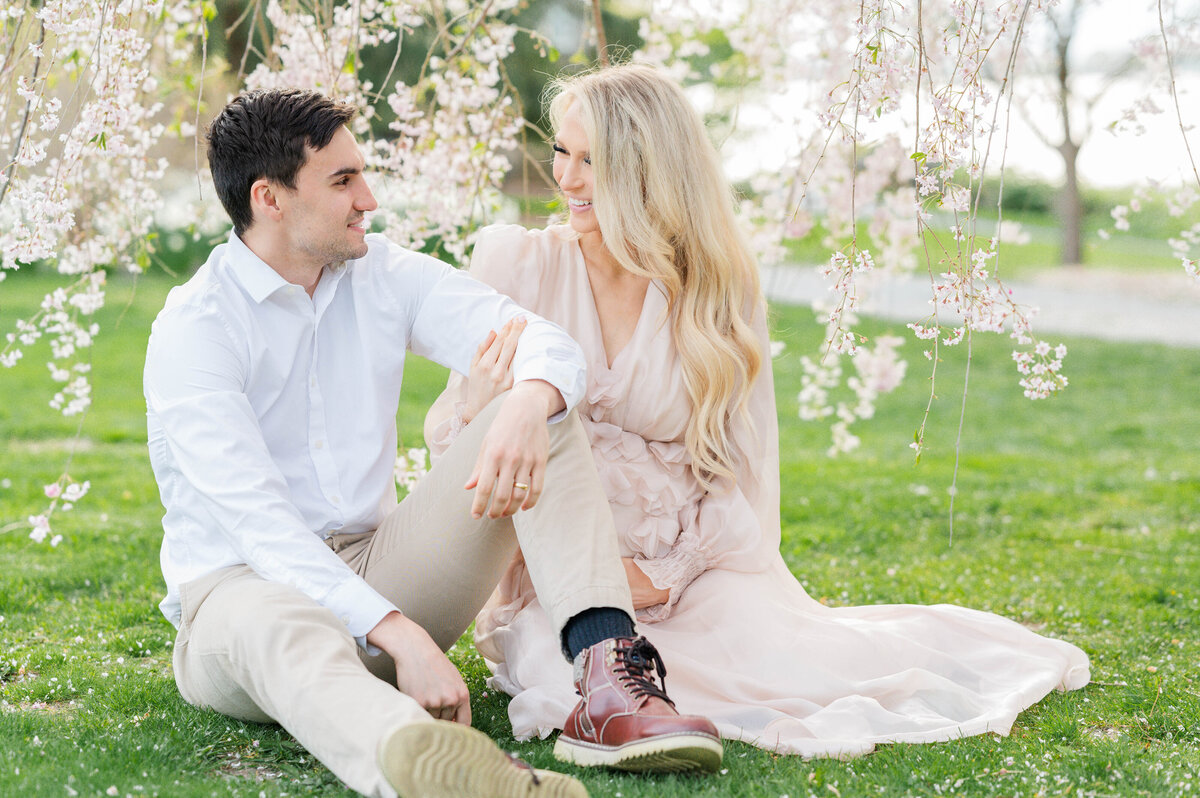 Husband and wife sitting with blooms around in Bristol, RI at Blithewold Mansion taken by best Maternity photographer in Rhode Island