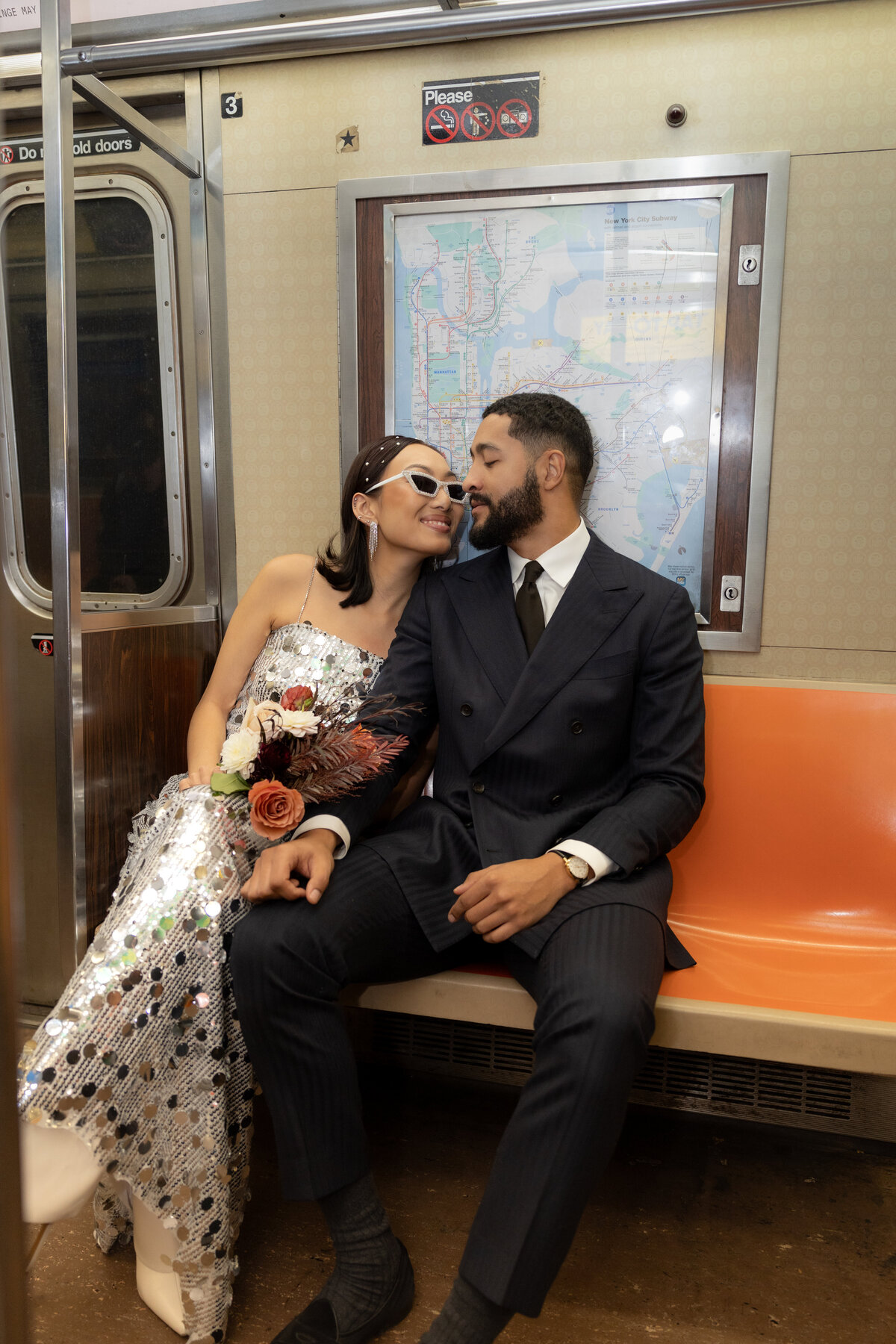 Bride sitting on iconic orange subway seats, holding a colorful bouquet during a modern NYC elopement.
