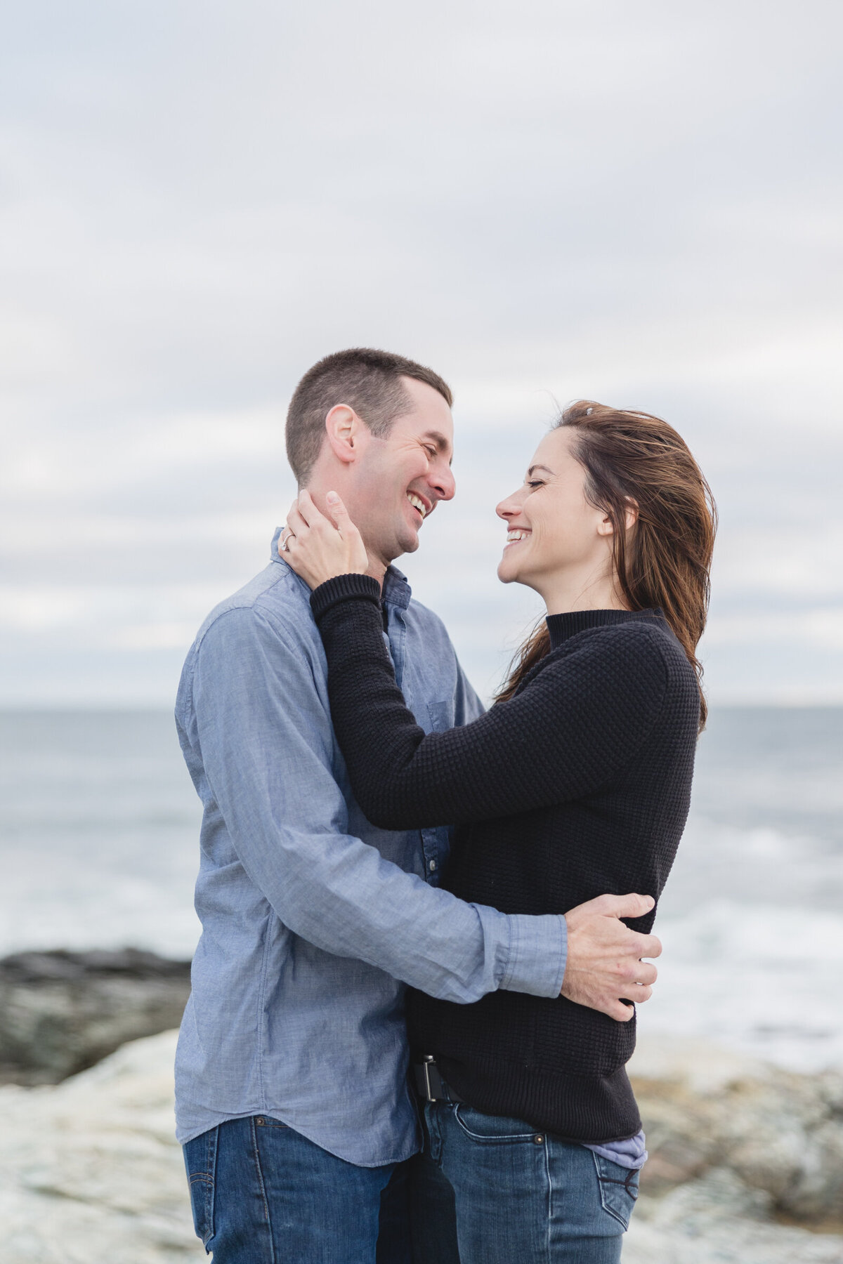 Engaged couple smile at each other in Newport during their engagement session
