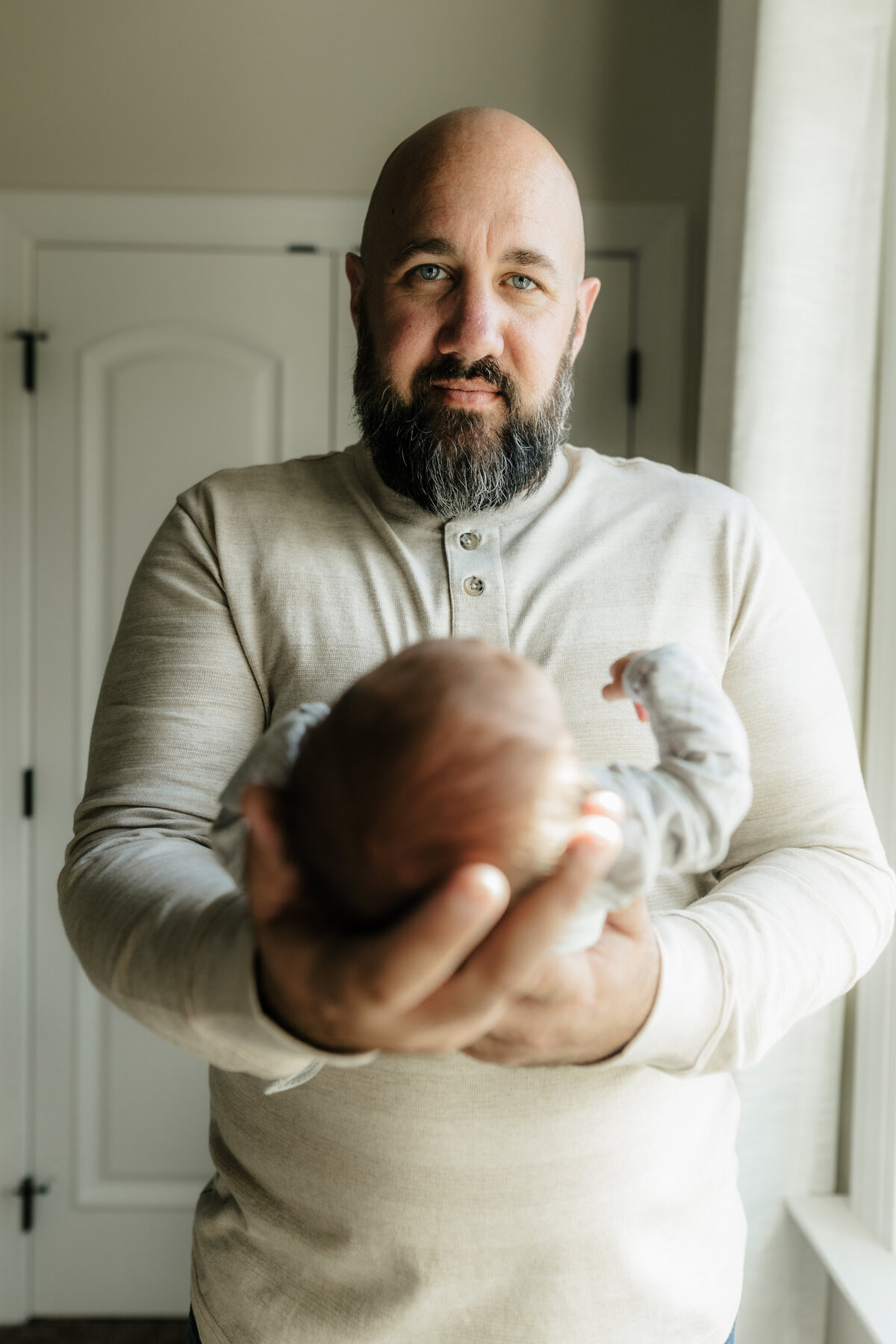 dad holding newborn baby boy in front of window by harrisburg pa newborn photographer