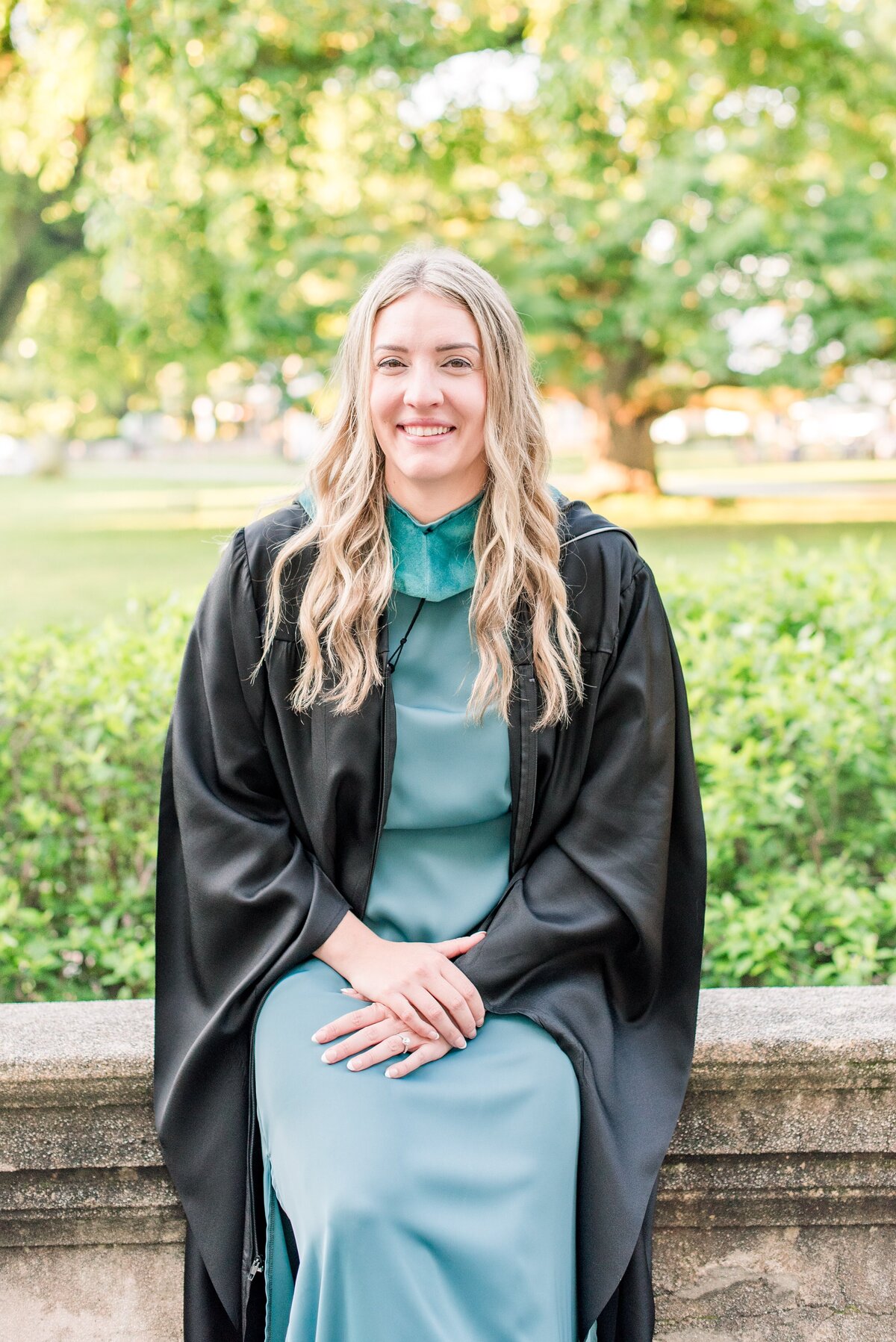 female grad teal dress with black regalia
